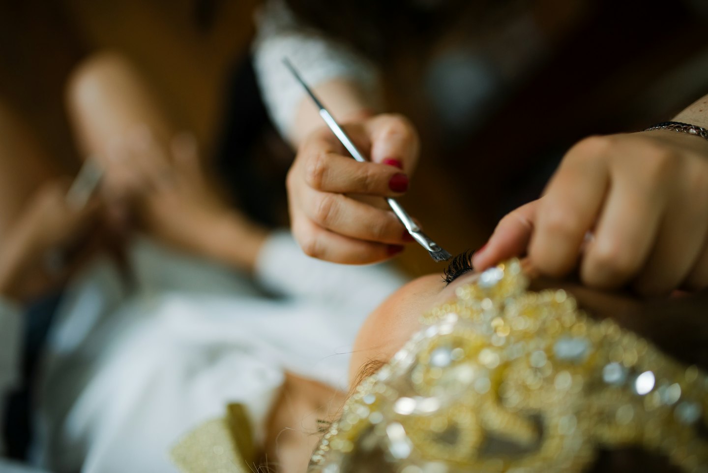 Makeup artist applying false eyelashes to a client's eye.